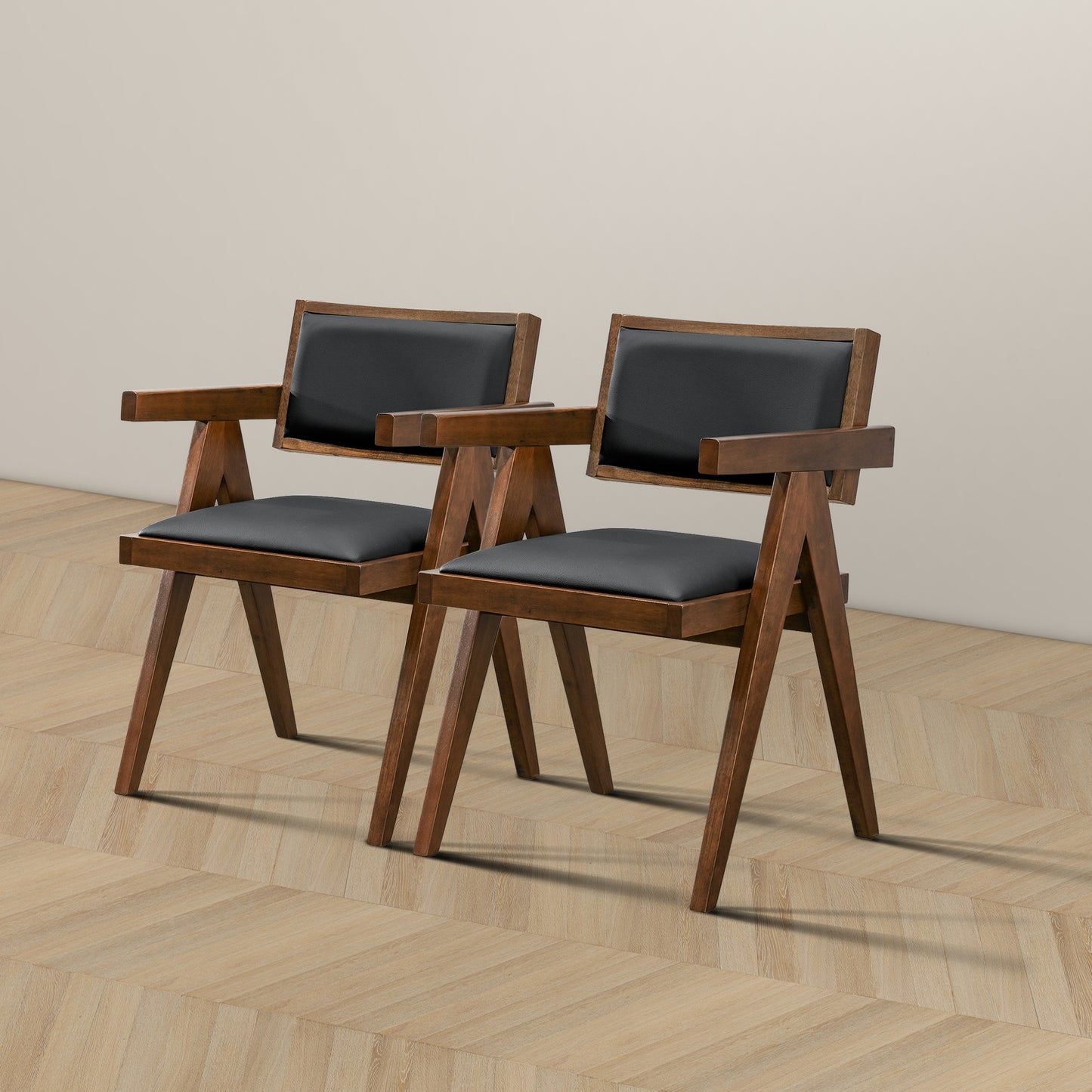 Pair of modern wooden armchairs with black cushions on wood floor, FredCo International furniture