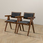 Pair of modern wooden armchairs with black cushions on wood floor, FredCo International furniture