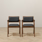 Pair of modern wood dining chairs with black cushions on light wood floor, FredCo International
