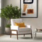 Modern living room with cream armchair, yellow pillow, potted plant, and abstract wall art
