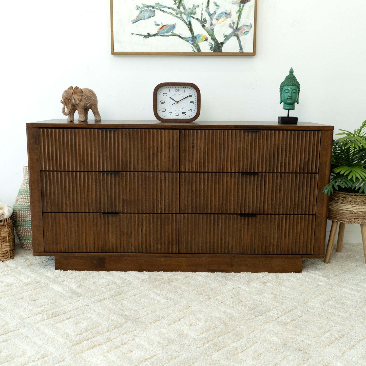 Modern wooden dresser with decor clock, elephant figurine, and green Buddha head on top.