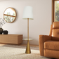 Modern living room with tan leather sofa, brass floor lamp, wooden cabinet, and round mirror