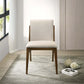 Modern beige upholstered dining chair with wooden frame on a rug, near a window and decor.