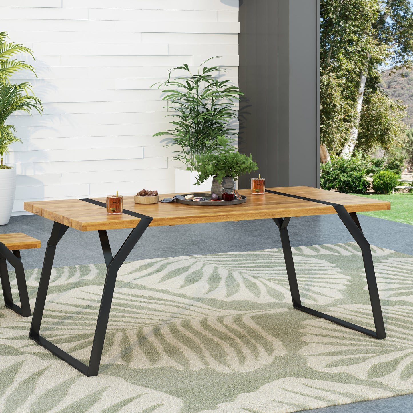 Modern wood dining table with black metal legs on leaf-pattern rug, patio setting, FredCo International