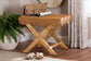 Wicker accent table with crossed legs in a cozy room, styled with a purse, magazine, and houseplant
