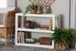 Modern white console table with vases, books, woven baskets, and plants in a cozy living room