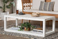 Modern white rectangular coffee table with books, plant, and decor in a stylish living room