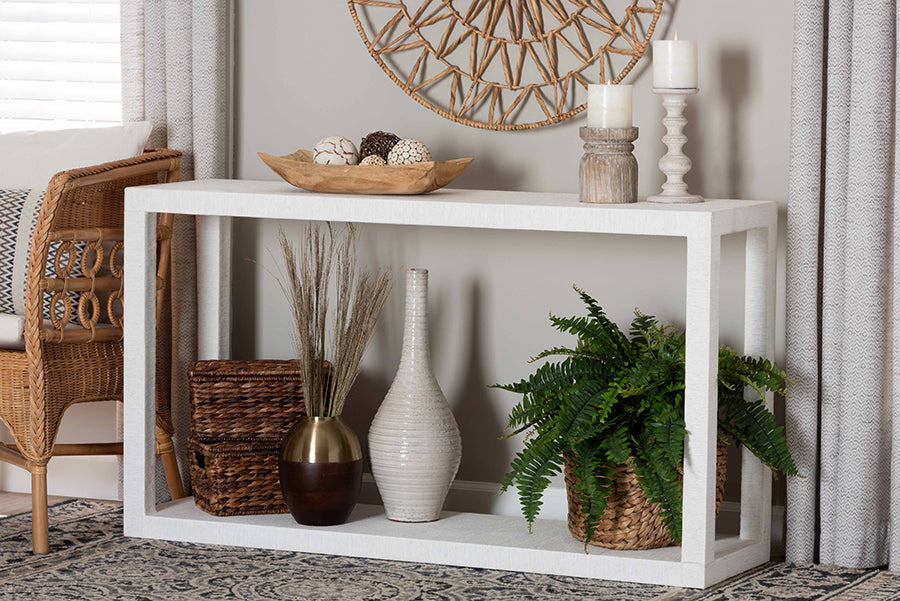 Modern white console table with decorative vases, baskets, greenery, and candles in a living room