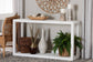 Modern white console table with decorative vases, baskets, greenery, and candles in a living room
