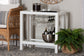 Modern white bar cart with glassware, wine bottles, and a plant, featured in home furniture decor.