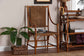 Rattan accent chair with woven seat in a cozy entryway, next to a green plant and umbrella stand.