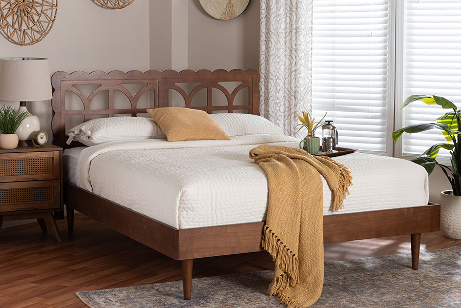 Modern wood bed frame with white bedding and tan throw in a bright, stylish bedroom setting.