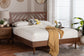 Modern wooden bed with geometric headboard, white bedding, and accent pillows in cozy bedroom