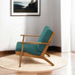 Mid-century modern lounge chair with teal upholstery and wood frame on round rug in a bright room