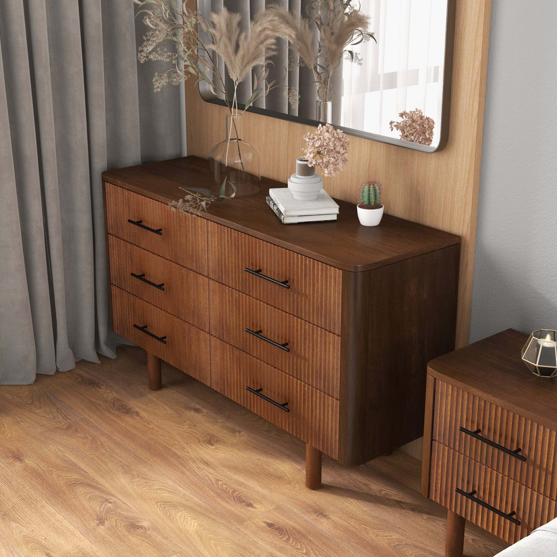 Modern wood dresser with black handles, decorative vases, cactus, and books in stylish bedroom