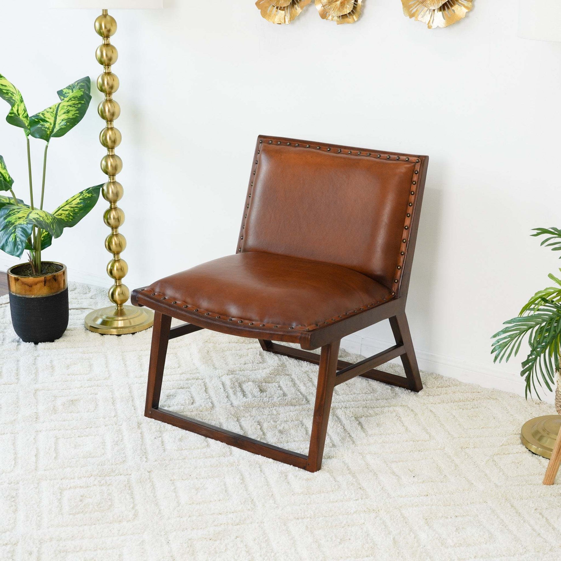 Mid-century modern brown leather accent chair in a bright living room with gold decor and plants