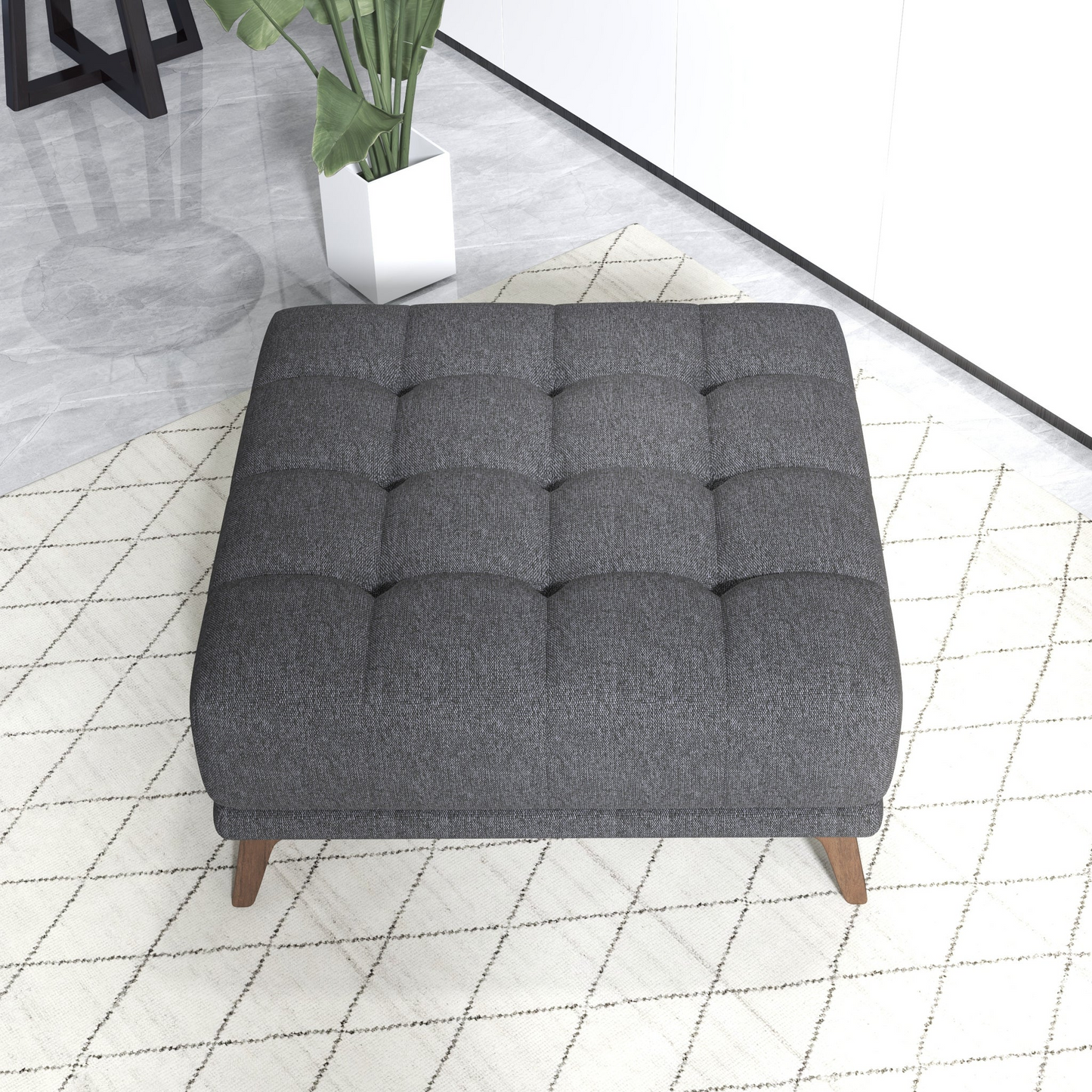 Modern tufted dark gray ottoman on patterned rug in contemporary living room