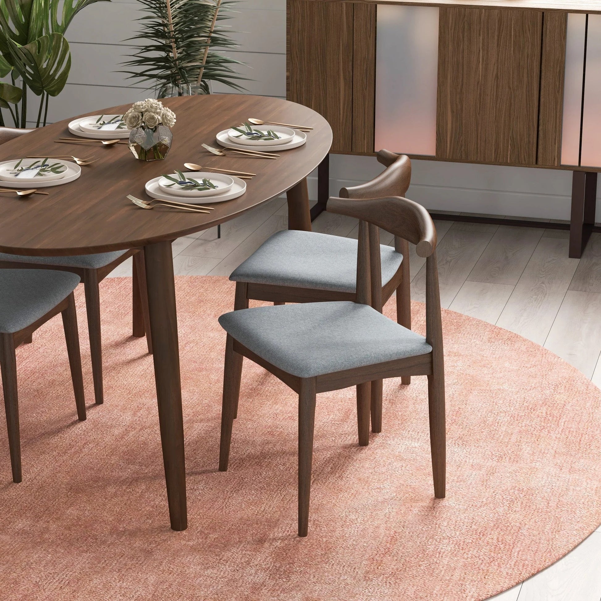 Modern wood dining table set with gray chairs on a pink rug, styled for FredCo International