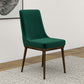 Green upholstered dining chair with dark wooden legs on a rug in modern home setting