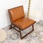 Modern brown leather accent chair with wooden frame on patterned rug in stylish living room