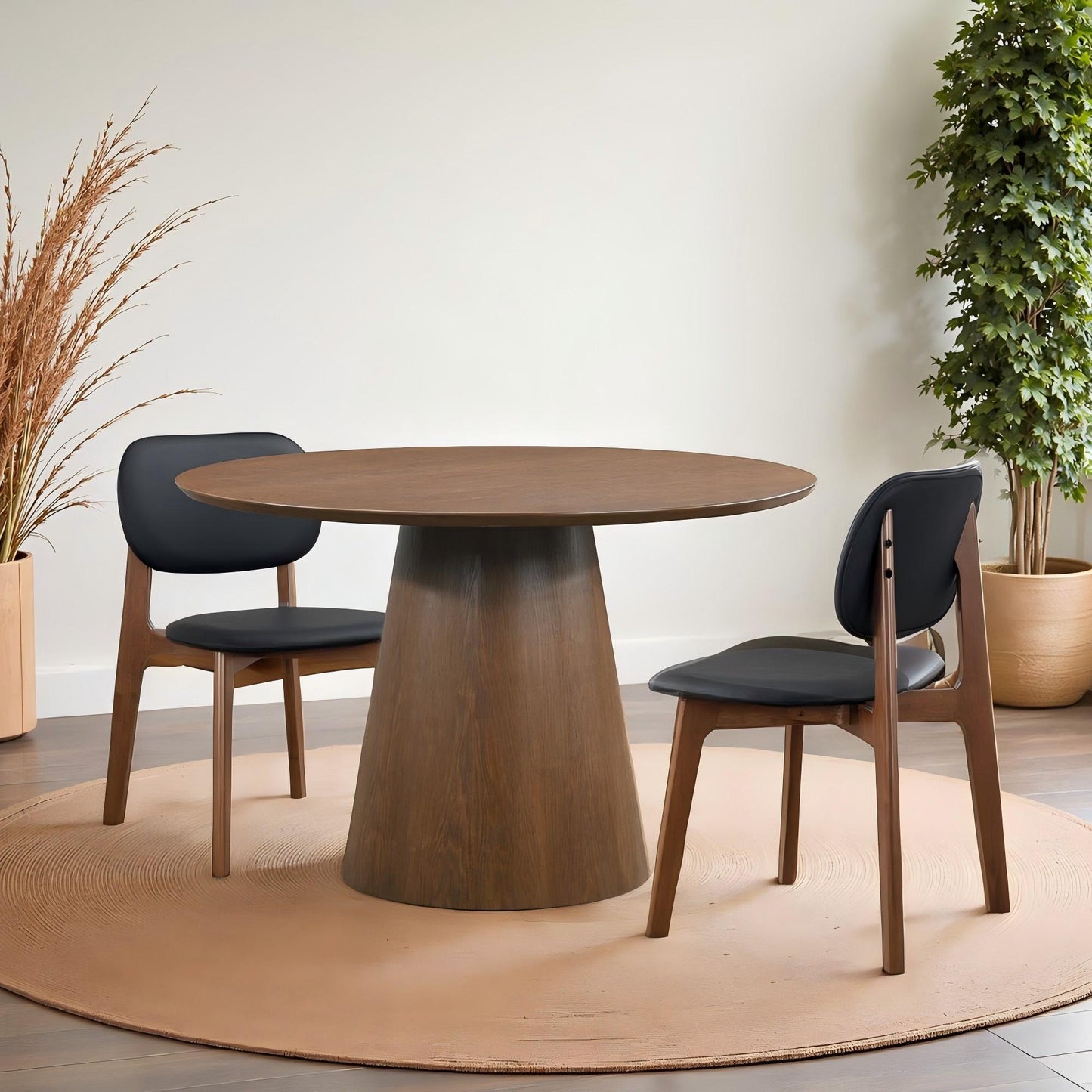Modern round wooden dining table with two black cushioned chairs in a stylish home setting