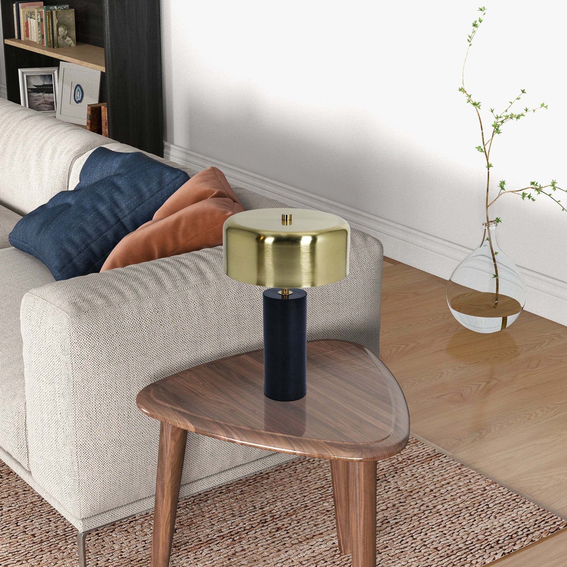 Modern gold table lamp on wood accent table beside beige sofa with cushions, FredCo International furniture