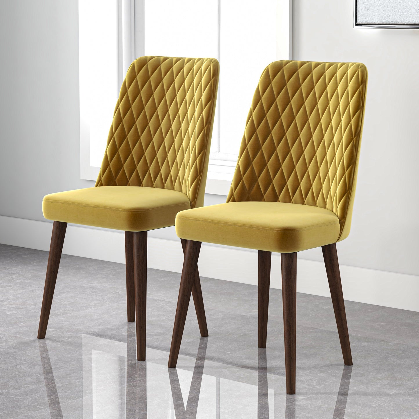 Pair of modern yellow velvet dining chairs with quilted backs and dark wood legs by window