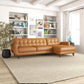 Mid-century tan leather sectional sofa in modern living room with bookshelves, lamp, and art.