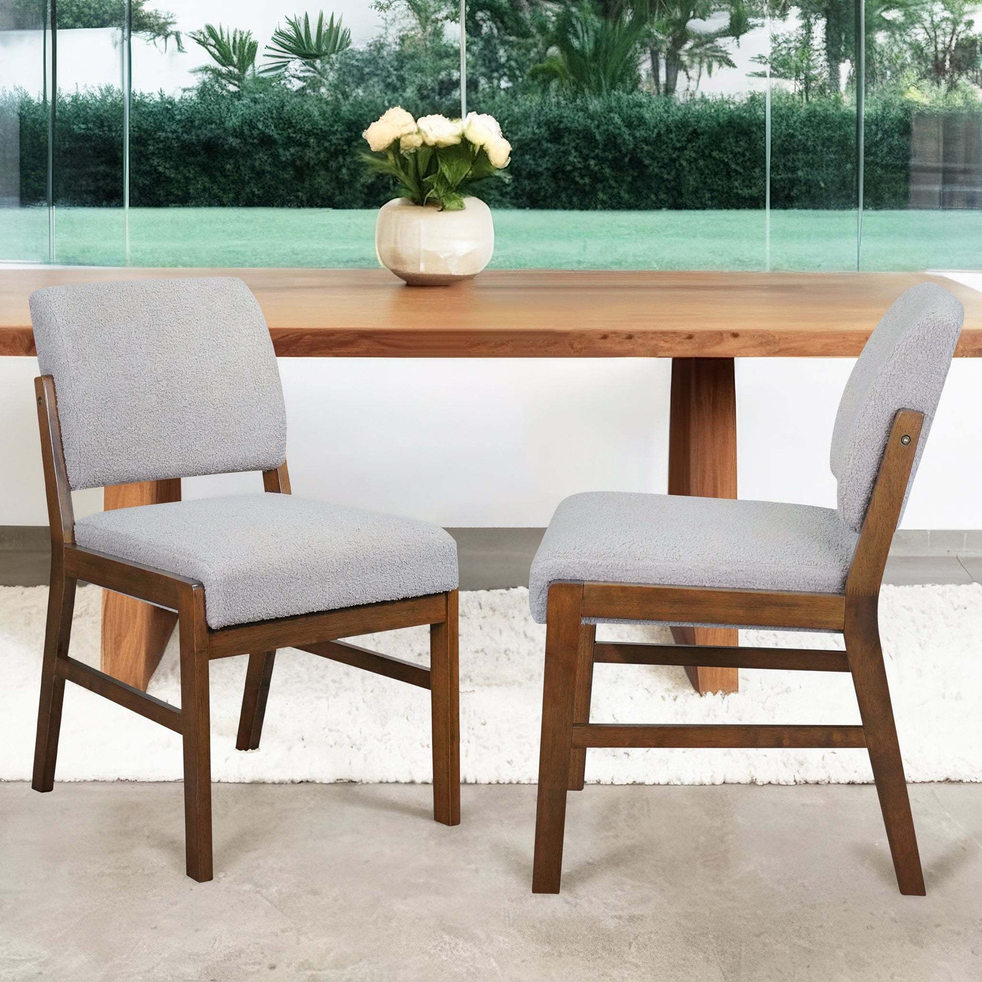 Modern dining room with two upholstered wooden chairs, wooden table, and vase of flowers