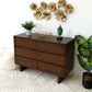 Modern wooden dresser with decor, gold wall art, houseplants, and textured rug in stylish room