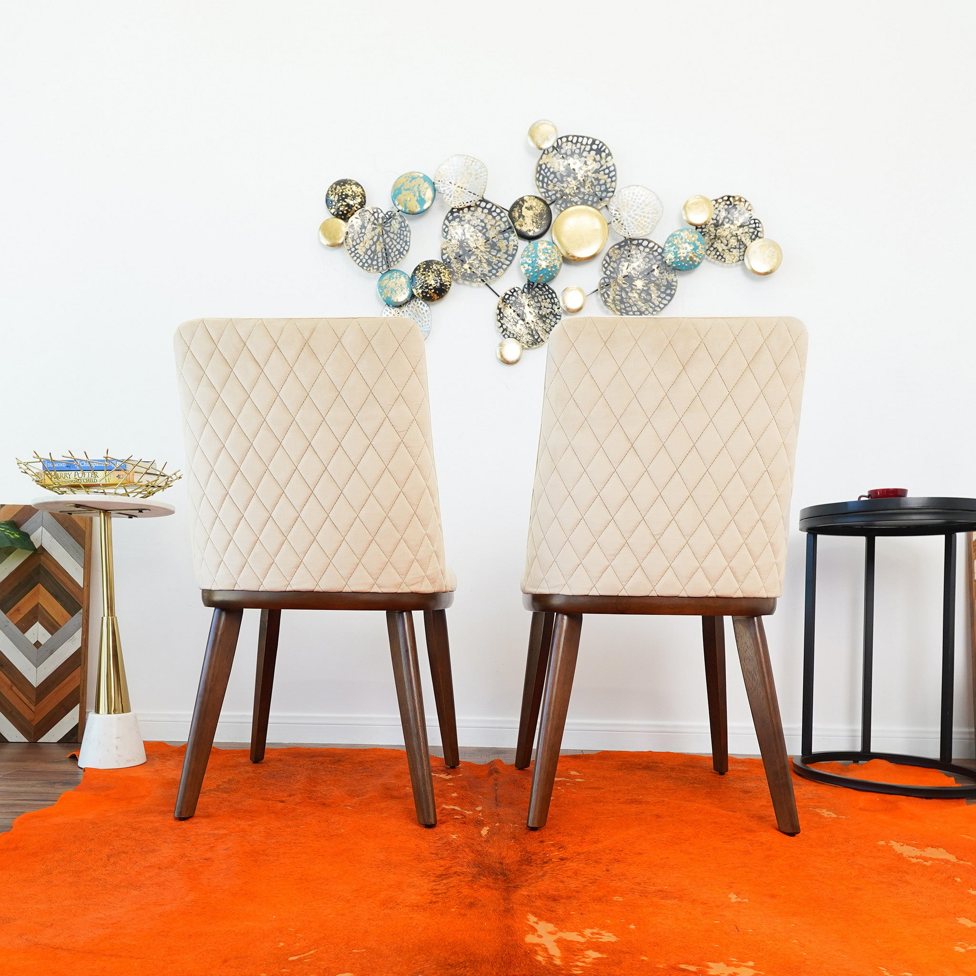 Modern beige quilted dining chairs on orange rug with abstract wall decor, FredCo International furniture