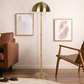 Modern living room with brass floor lamp, brown leather sofa, accent chair, and wall art