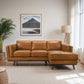 Modern tan leather sectional sofa in bright living room with floor lamp and mountain wall art