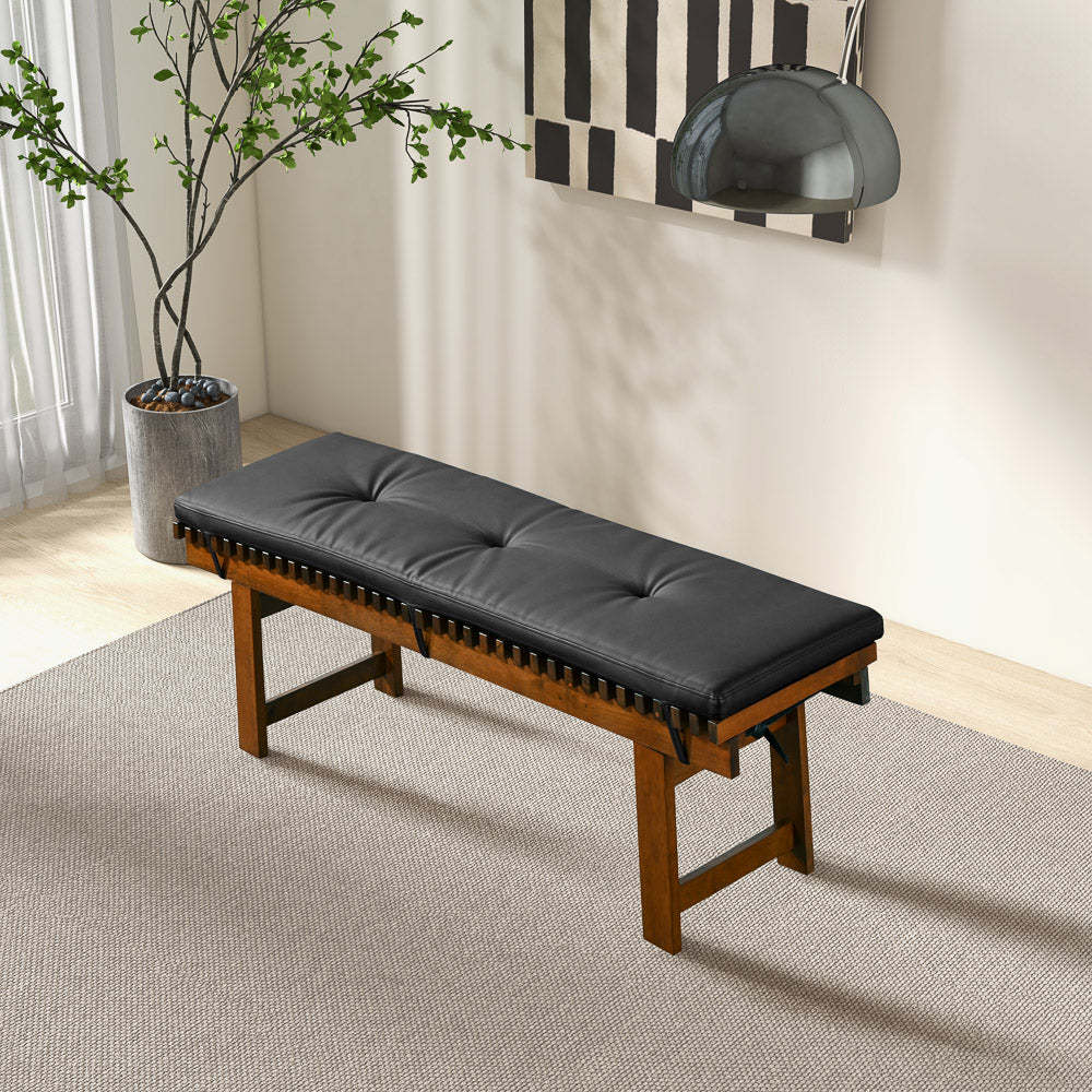 Modern wood bench with black tufted cushion in a bright room with art and potted plant