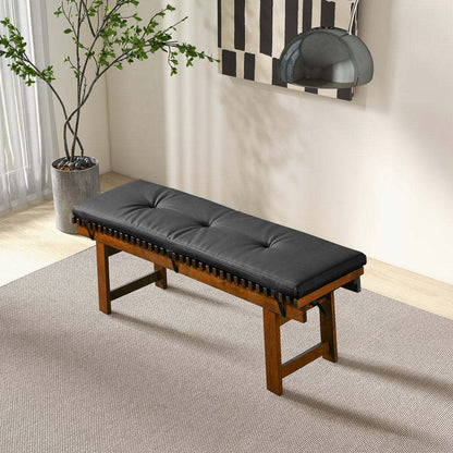Modern wood bench with black tufted cushion in a bright room with art and potted plant