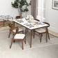 Modern wooden dining table set with four chairs, set for dinner, in a bright living room.