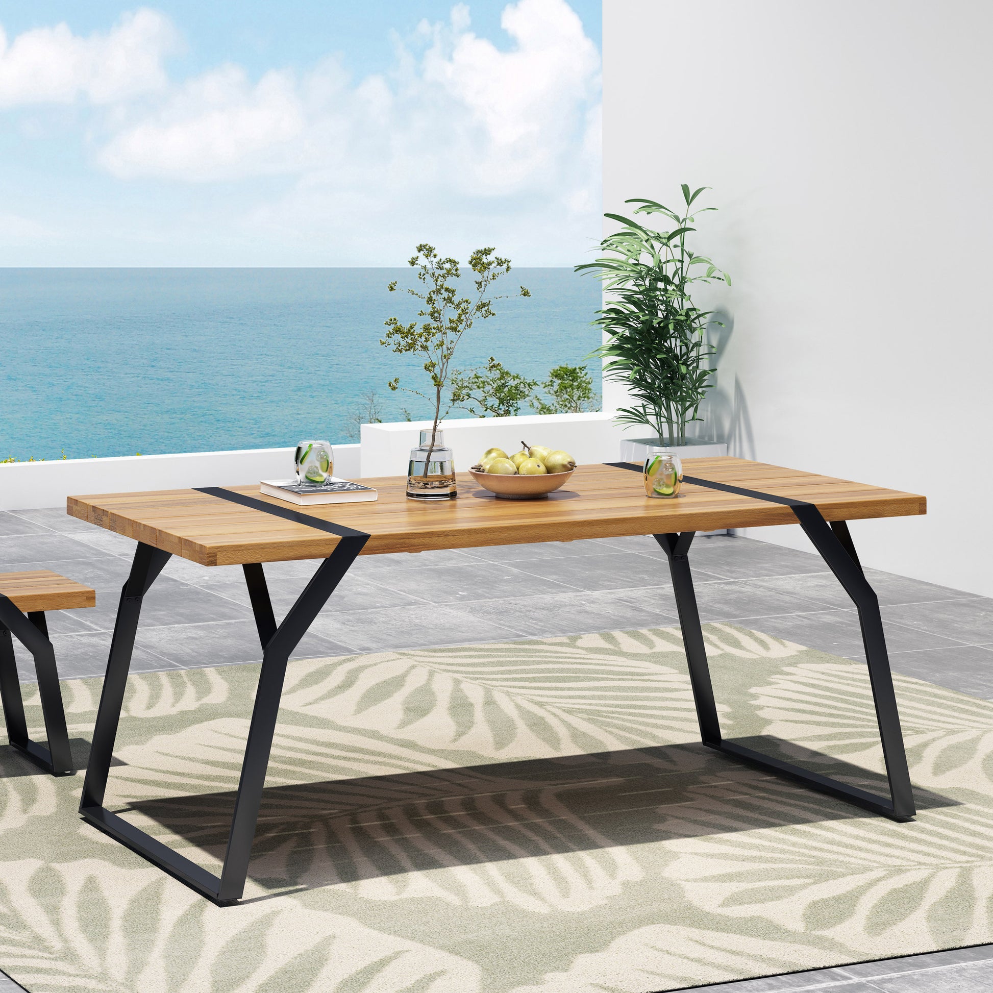 Modern wood dining table with black metal legs on patio, ocean view, and decorative plants