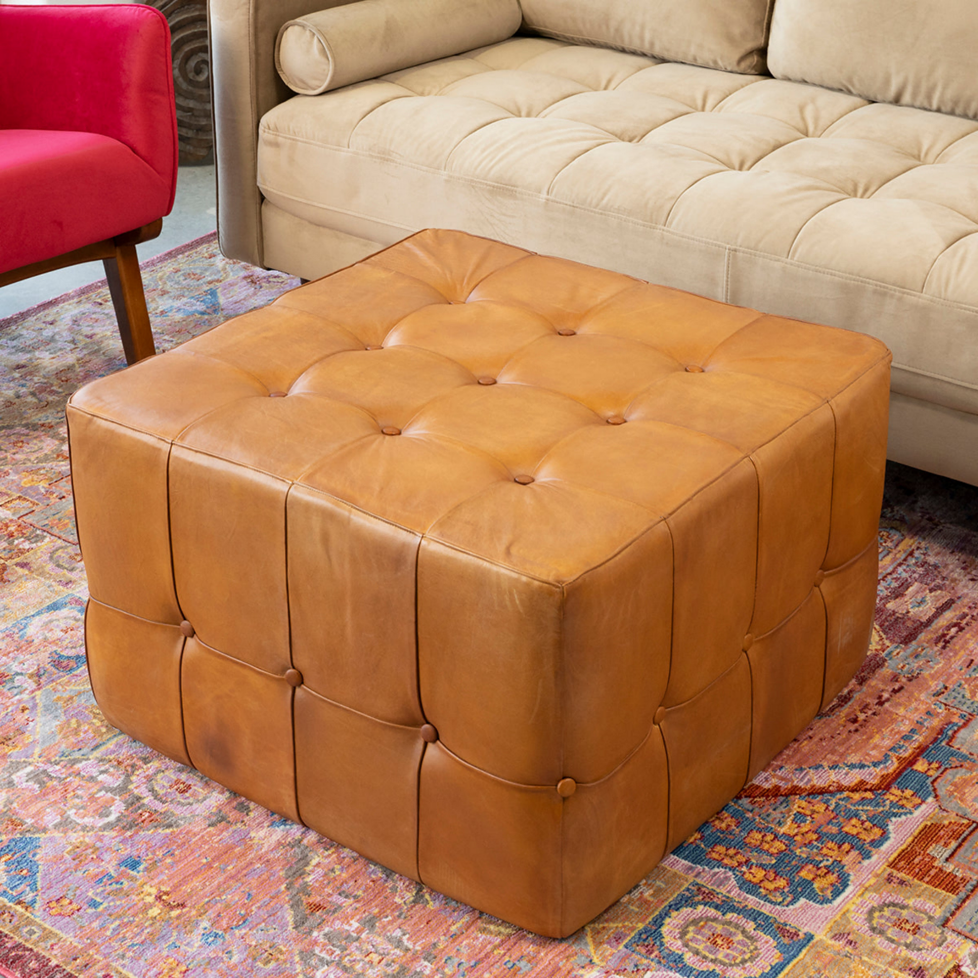 Tufted leather ottoman in modern living room with beige sofa and colorful rug