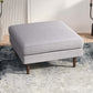 Modern light gray ottoman with wood legs on textured rug, stylish home furniture