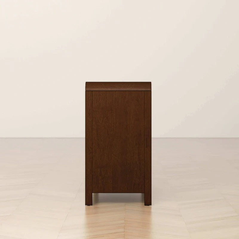 Dark wood nightstand side view in modern room, FredCo International furniture.