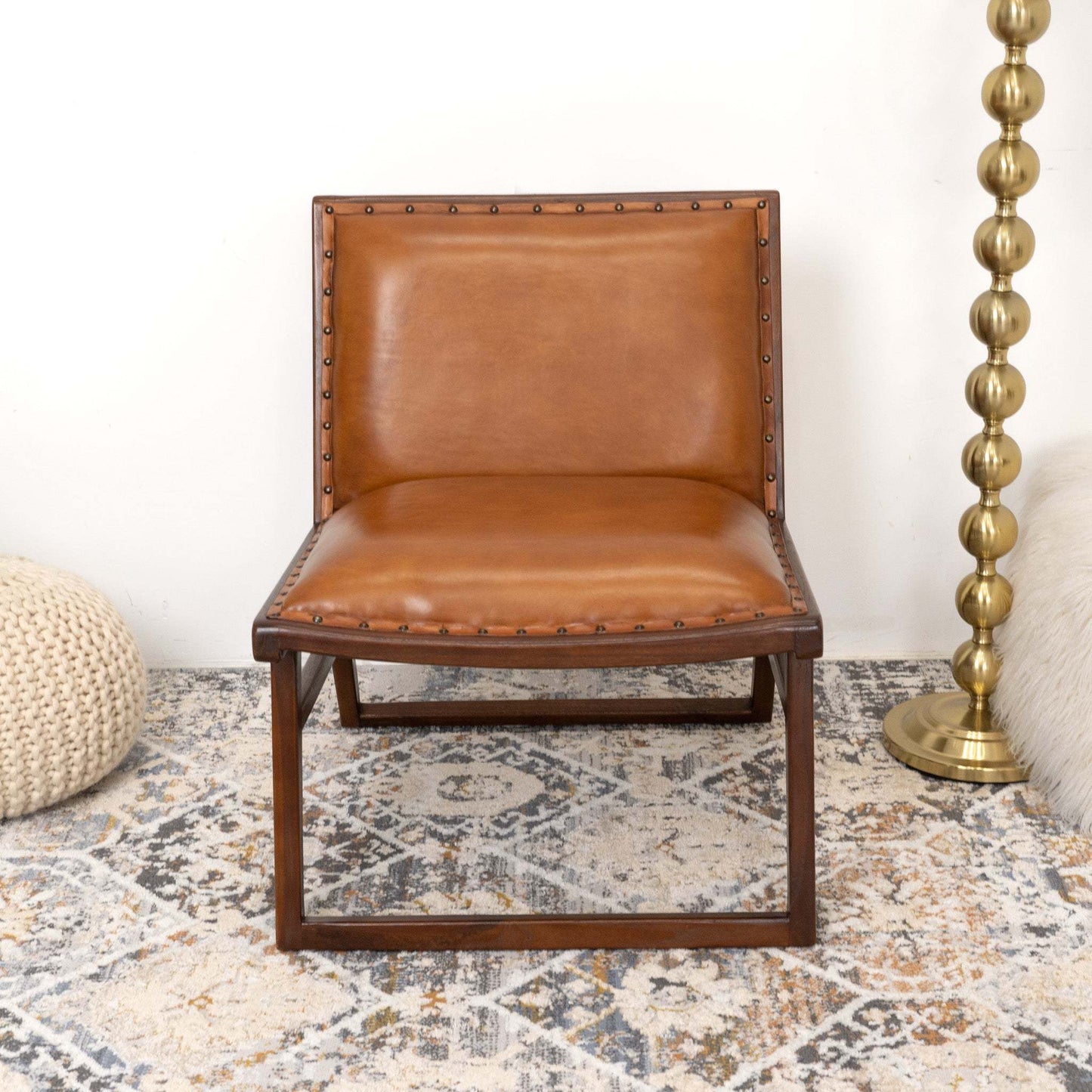 Modern brown leather accent chair with wood frame on patterned rug in cozy living room