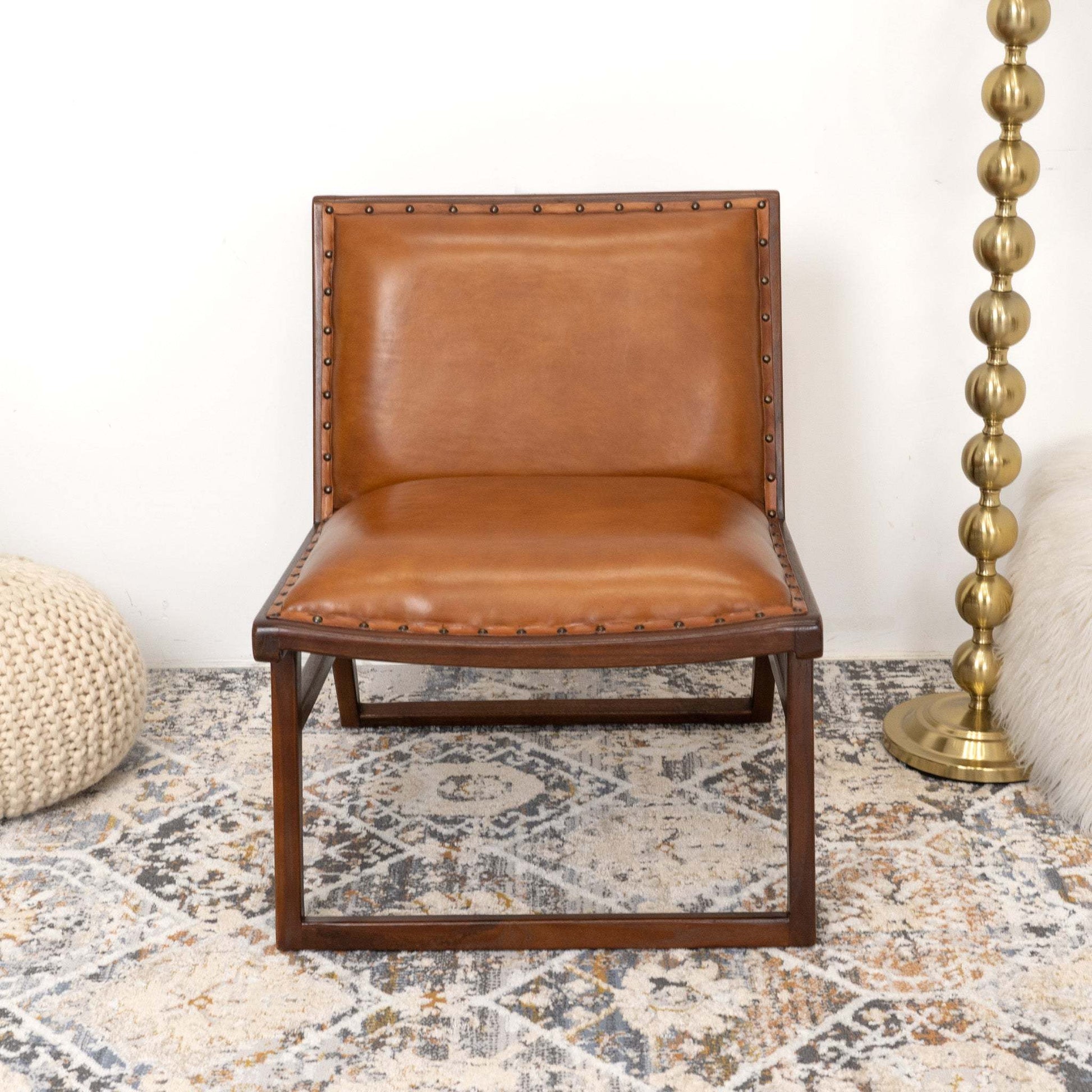 Modern brown leather accent chair with wood frame on patterned rug in cozy living room