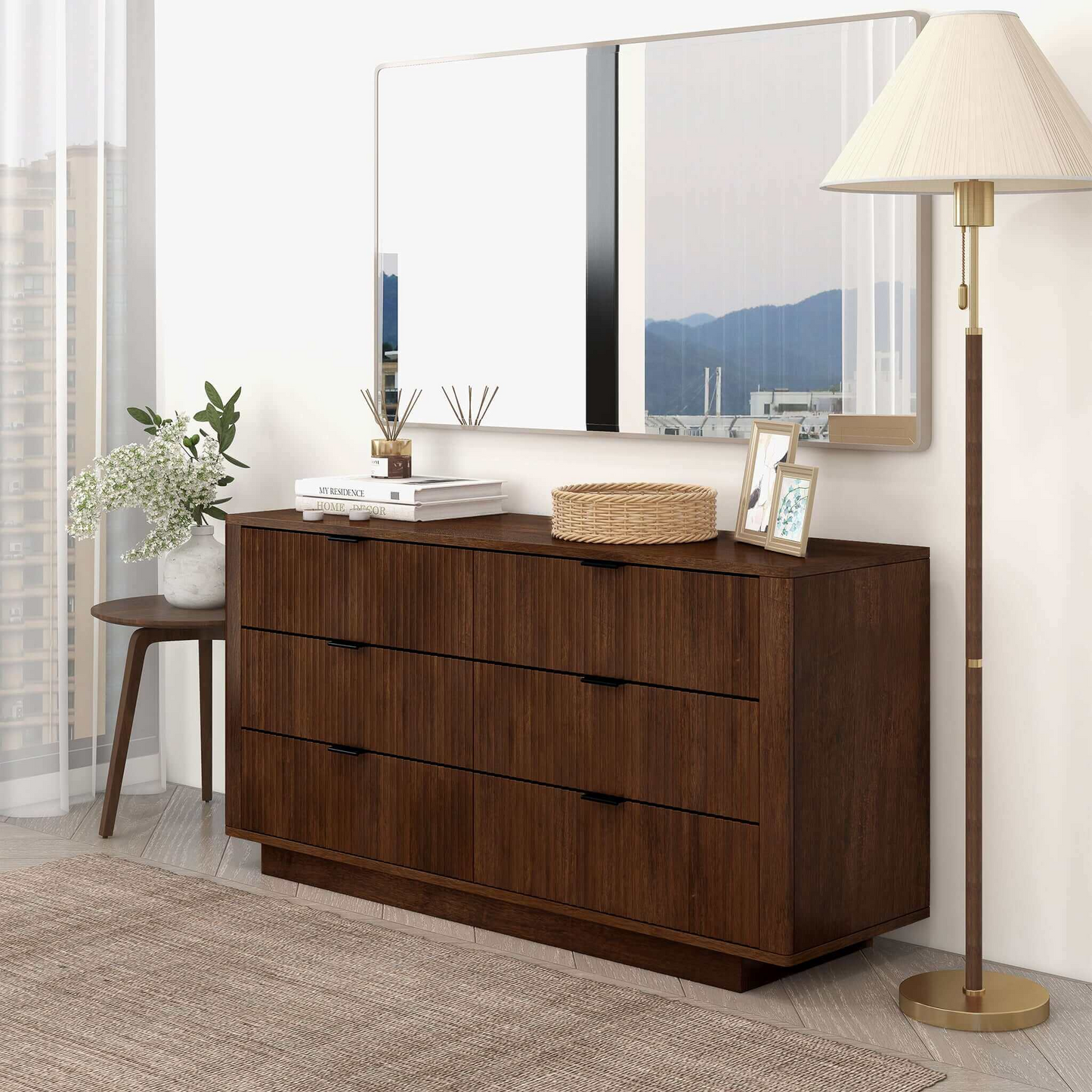 Modern bedroom setup featuring a dark wood dresser, decor accents, mirror, and floor lamp