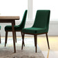 Modern green dining chairs with wood legs next to a wooden table in a bright home setting