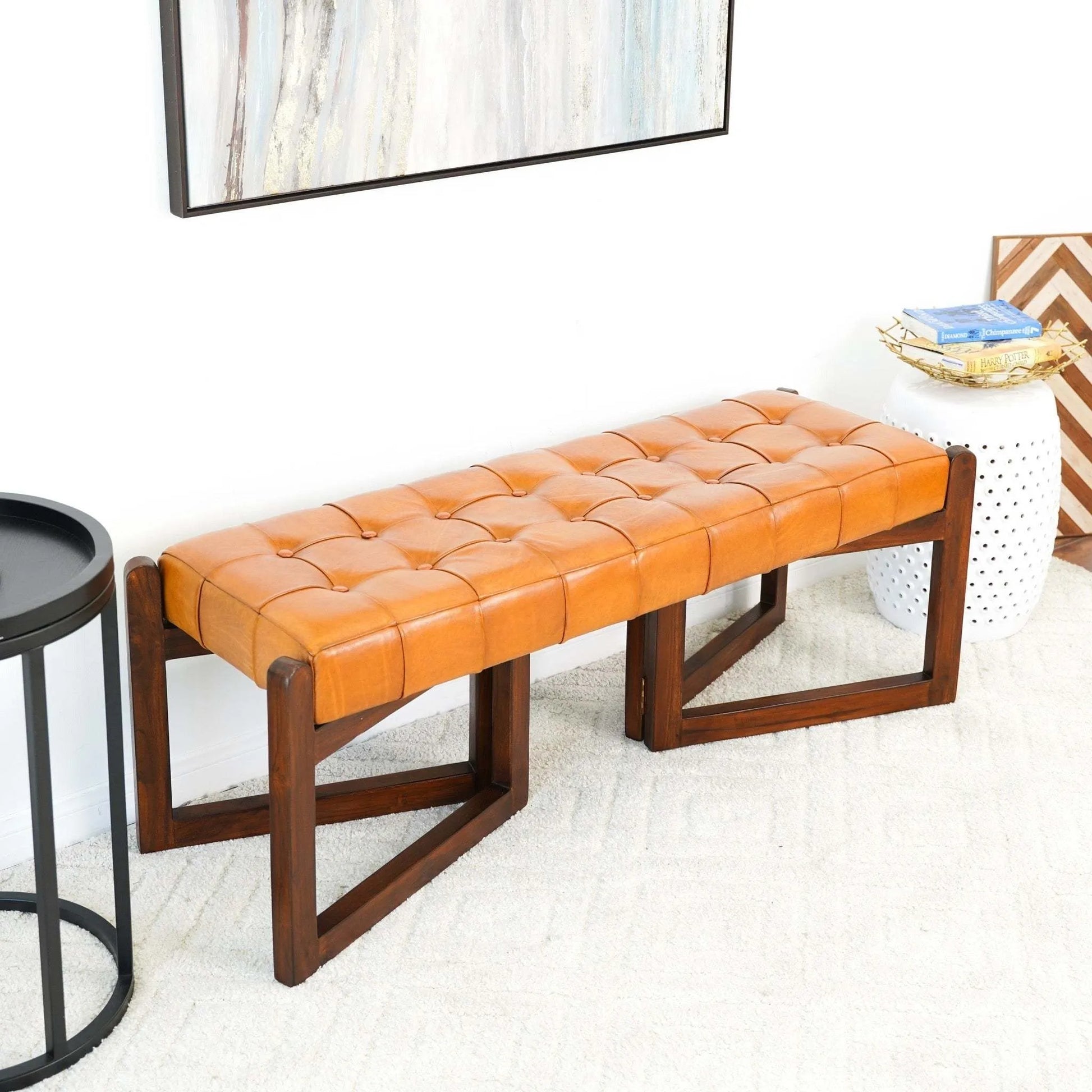 Modern tan leather tufted bench with wooden legs in a bright living room, FredCo International furniture