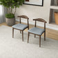 Pair of modern wood dining chairs with gray cushions in a bright living room, FredCo furniture