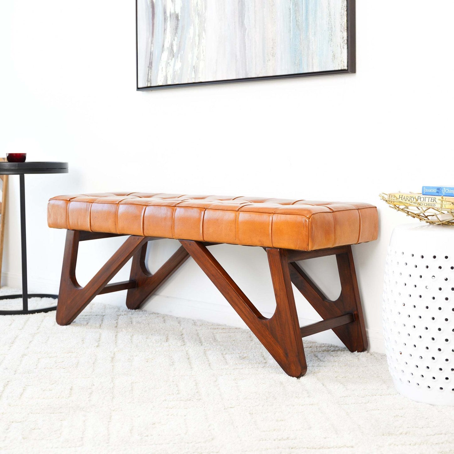 Modern tan leather bench with wood legs in a bright, contemporary living room setting.