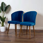 Pair of modern blue velvet accent chairs with wooden legs on hardwood floor, next to potted plant