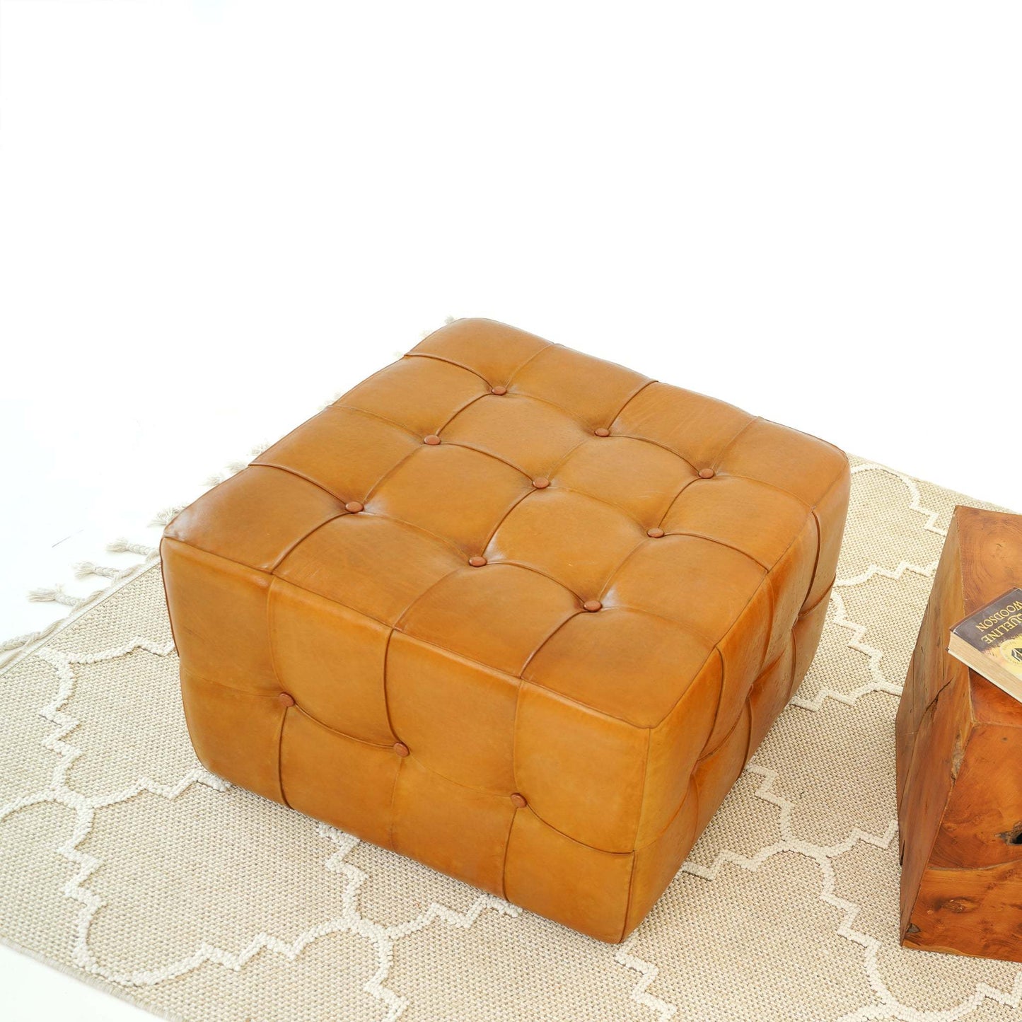 Square tufted leather ottoman on beige patterned rug, modern home furniture from FredCo International