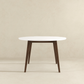 Modern round dining table with white top and dark wood legs, minimalist home furniture